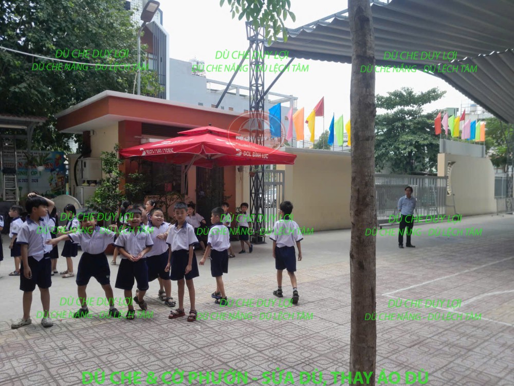 Dù đỏ tại sân Trường Tiểu học Đặng Thùy Trâm, gần khu vực học sinh hoạt động.