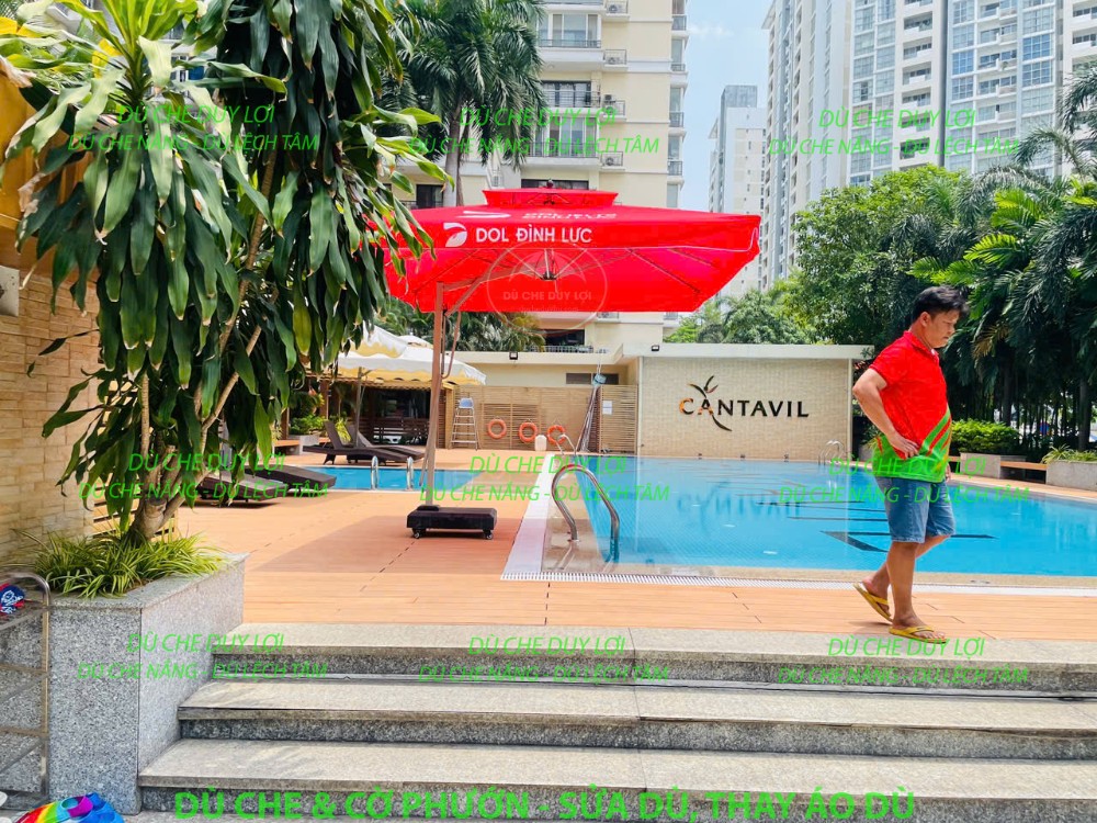 Dù đỏ in DOL Đình Lực cạnh hồ bơi trong khuôn viên Cantavil.