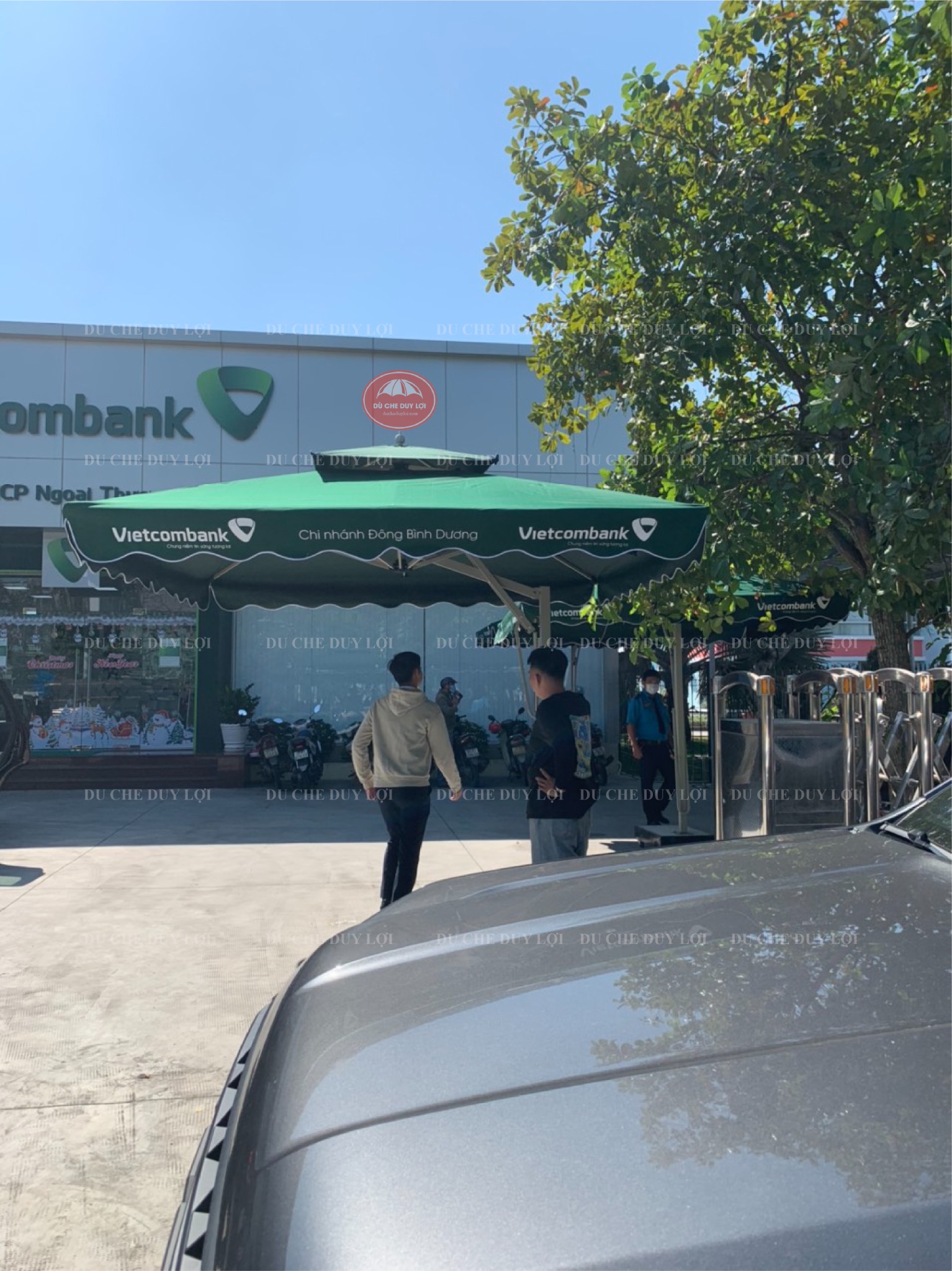 Dù xanh rêu phía trước điểm giao dịch có biển hiệu Vietcombank.