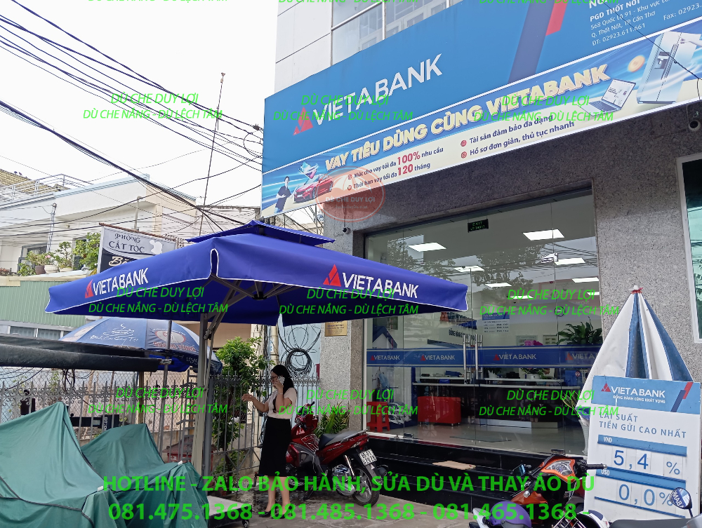 Dù VietABank với trụ lệch tâm đặt cạnh biển thông tin trước phòng giao dịch.