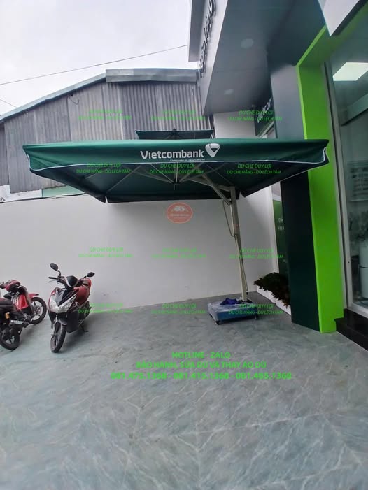 Dù Vietcombank màu xanh đậm với trụ lệch tâm bên cạnh khu vực tiếp cận phòng giao dịch.
