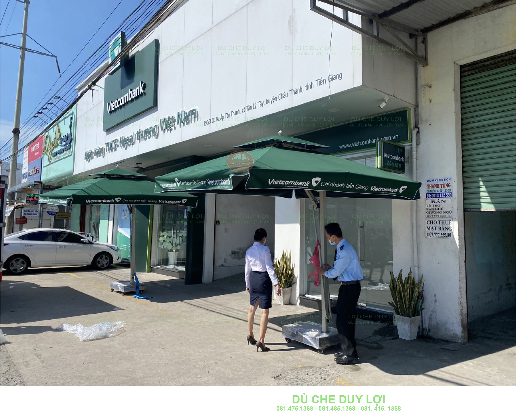 Cụm dù lệch tâm vuông hai tầng in logo Vietcombank trong quá trình giao lắp trước phòng giao dịch.
