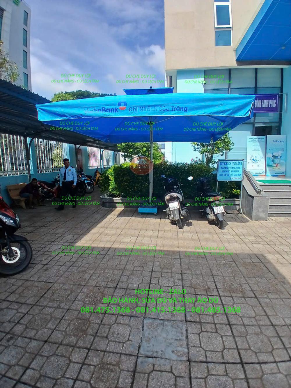 Tán dù xanh in nhận diện VietinBank nhìn từ góc bên, với bộ đế trên nền sân lát.